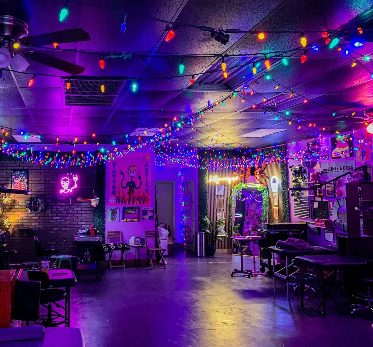 Wizardry Ink studio: brick walls, hand-painted art and coloured string lights under purple neon